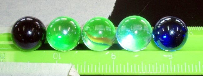 Five marbles on a green plastic ruler
