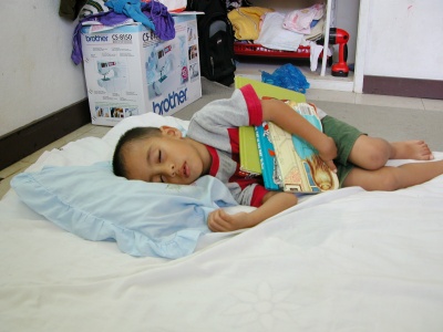 Marlin sleeps holding his books and rubbing the fringe of his pillow.